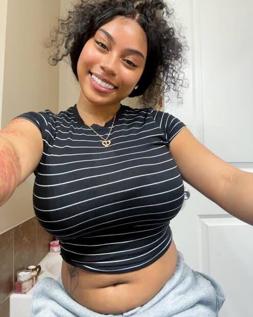 Playful curvy UK phone chat model Caleya Brighton smiling with natural curls and relaxed confident presence