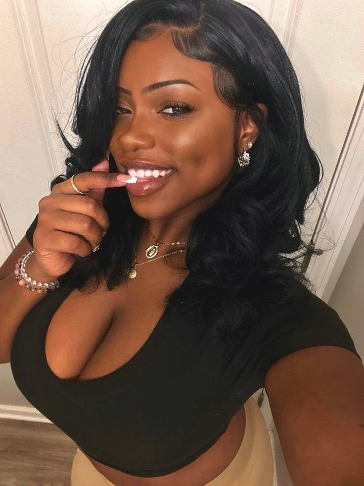 Playful curvy UK phone chat model Zarielle Moon smiling with soft waves and a confident flirty pose indoors