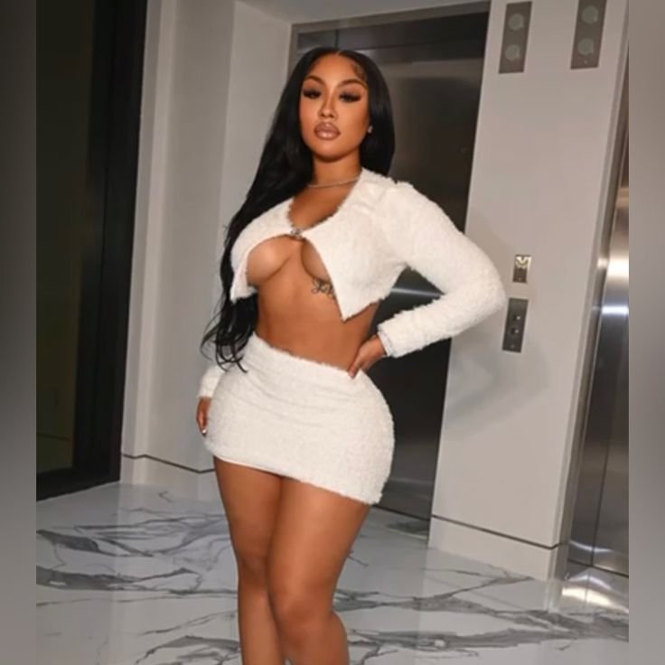 Confident curvy woman wearing a white textured two-piece outfit standing indoors