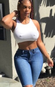 Confident woman wearing a white cropped top and blue jeans standing outdoors