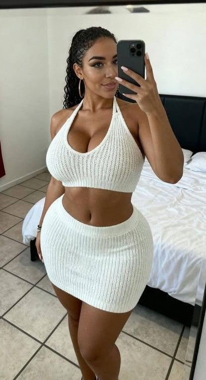 Curvy woman in a white outfit taking a mirror selfie representing phone sex chat UK and adult chat with horny girls