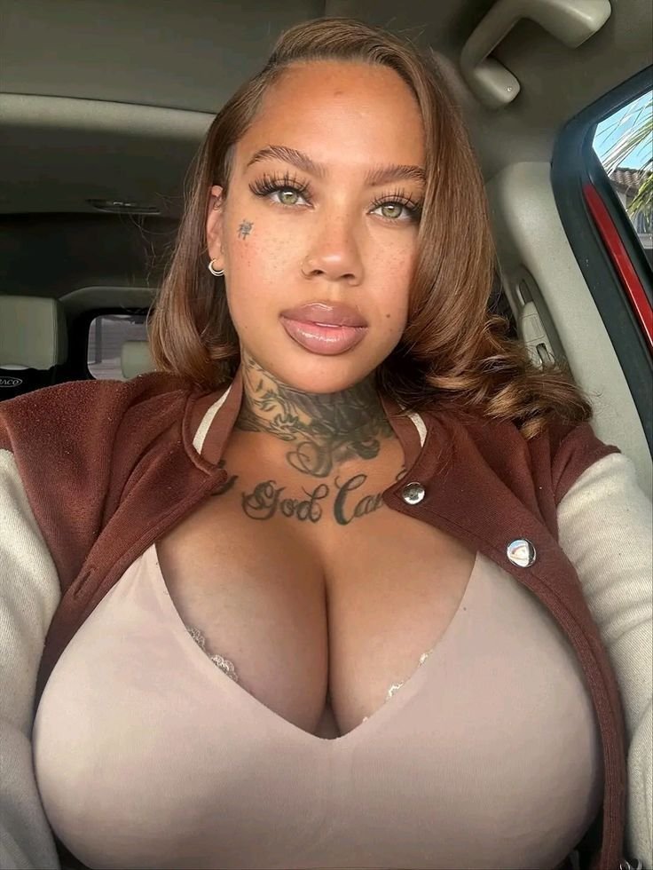 Confident curvy UK phone chat model Ravina Lux with tattoos and soft glam makeup
