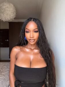 Elegant curvy woman with long braids wearing a black strapless top indoors