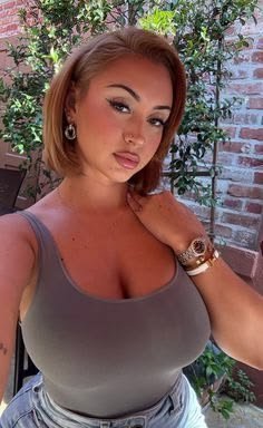 Luxury FemDom companion with copper bob hairstyle Elegant curvy woman in grey fitted top Premium fetish phone chat profile image Confident dominant female companion portrait Sophisticated FemDom profile photograph Stylish premium fantasy companion Curvy luxury companion portrait