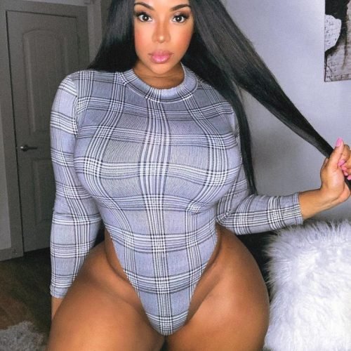 Confident curvy woman wearing a fitted plaid bodysuit indoors with sleek long hair