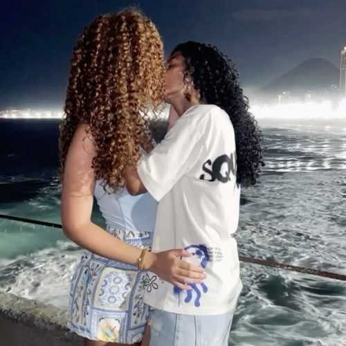 Girls on girls chat UK profile featuring two women by the seaside Lesbian phone chat UK female duo with natural curly hair Women seeking women chat profile on a coastal walkway Girls on girls phone chat UK profile image Lesbian chat lines UK confident female pair Adult chat UK girls on girls category profile