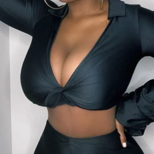 Elegant curvy woman wearing a fitted black outfit and head wrap posing confidently indoors