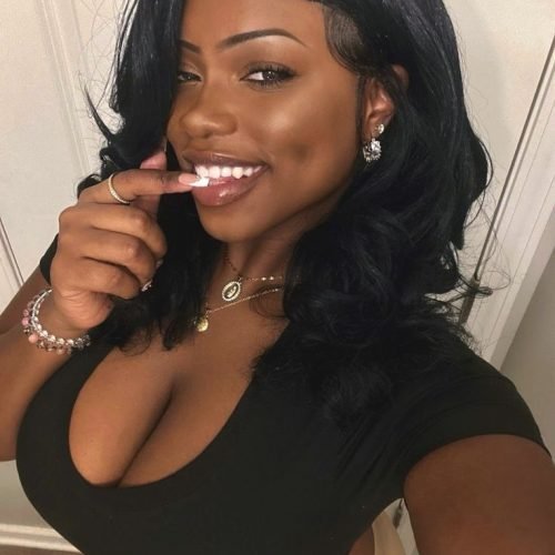 Playful curvy UK phone chat model Zarielle Moon smiling with soft waves and a confident flirty pose indoors