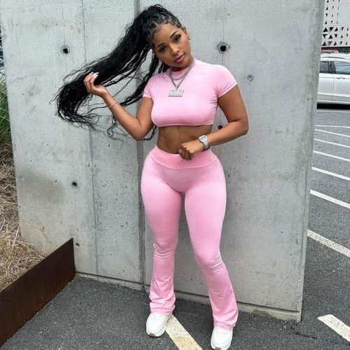 Curvy FemDom companion wearing pink activewear Confident woman with long curly ponytail Premium fetish phone chat profile image Stylish dominant female companion portrait Curvy fantasy chat profile photograph Sporty FemDom companion profile picture