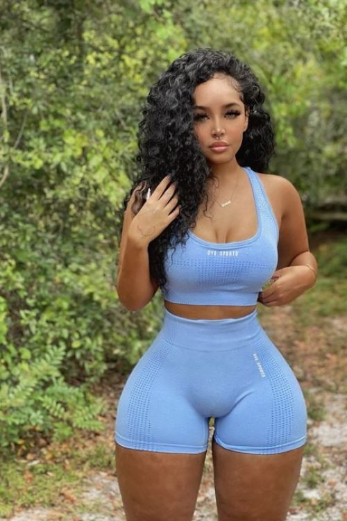 Curvy athletic woman wearing a blue workout set outdoors with confident, natural pose