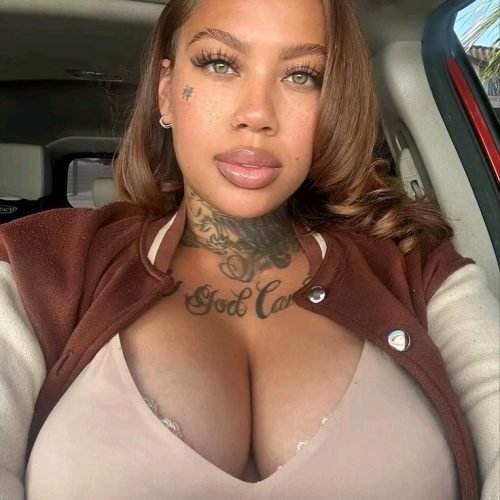 Confident curvy UK phone chat model Ravina Lux with tattoos and soft glam makeup
