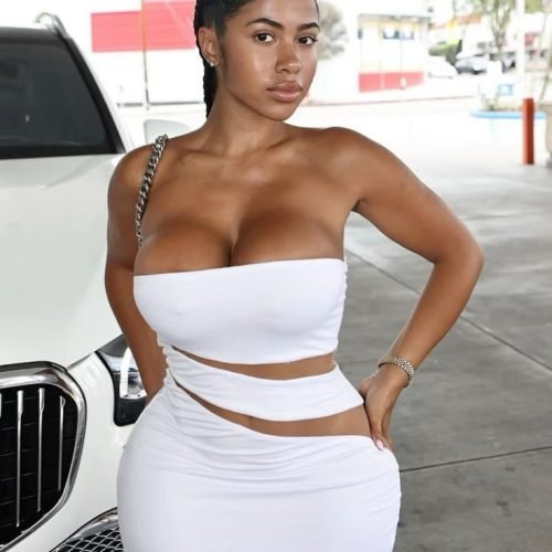 Refined curvy UK phone chat model Elowyn Harté in a white outfit with confident composed presence