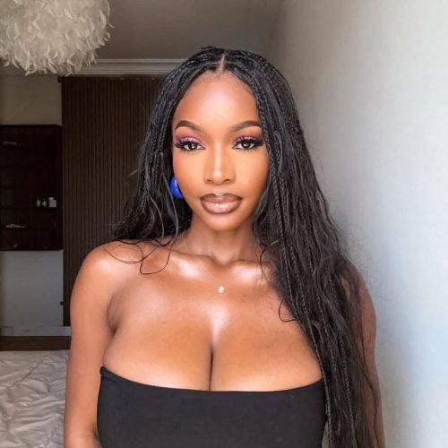 Elegant curvy woman with long braids wearing a black strapless top indoors