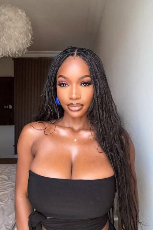 Elegant curvy woman with long braids wearing a black strapless top indoors