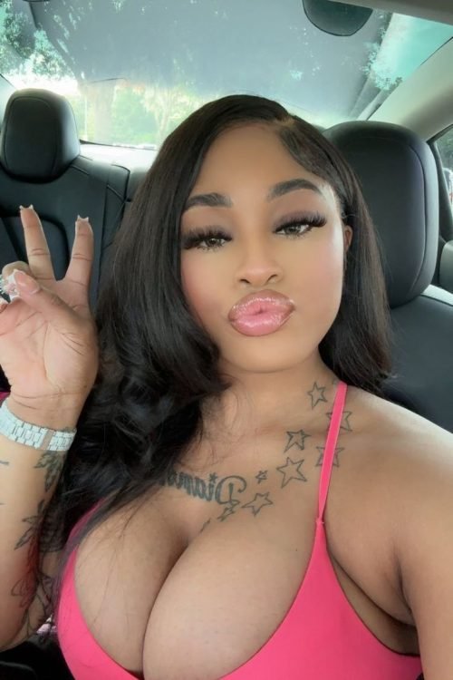 Playful curvy UK phone chat model Lunara Skye taking a car selfie with a peace sign and confident flirty expression